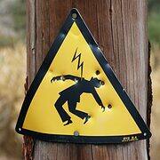 Danger! Electrocution sign attached to a tree trunk.