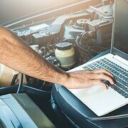 Laptop sitting on the open hood of a car