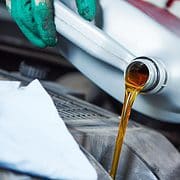 Person pouring a gallon of oil into a car engine