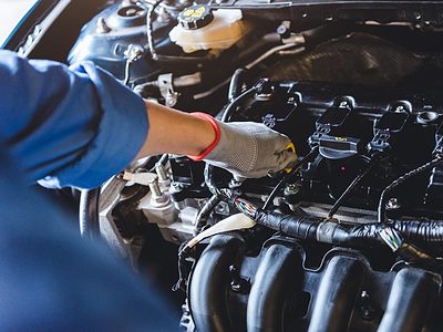 Person holding the engine oil dipstick handle of a car