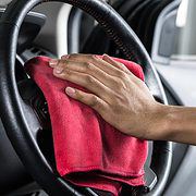 using a red towel to clean a car steering wheel