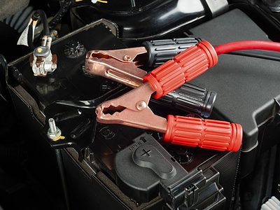 red and black jumper cable clamps on top of a car battery