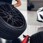 Technician holding a car tire with a white Camry in the background