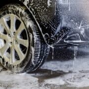 Black car and parts of ground covered in soap